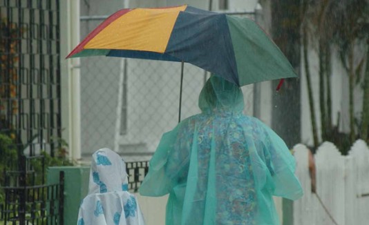 Señora u niña usan capas para taparse de la lluvia