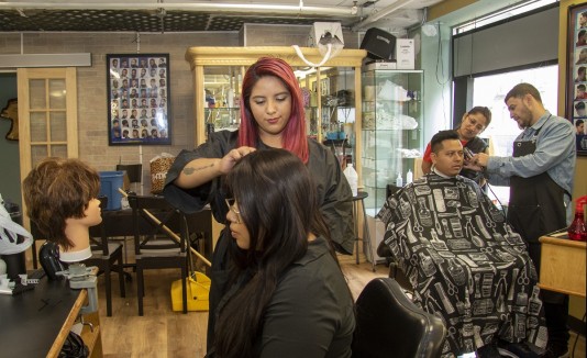 Unos estudiantes de la Escuela de Belleza Parisien cortan el pelo a unos clientes
