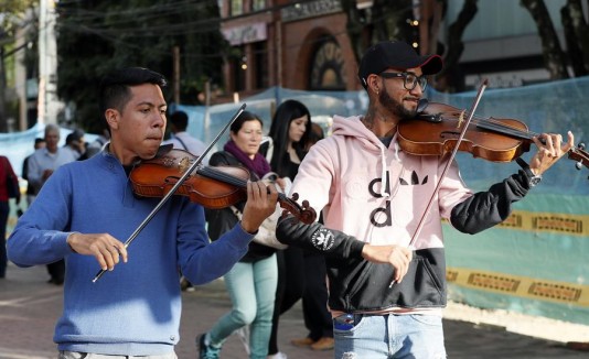 los músicos venezolanos Ángel García (violín), y Erick Sánchez (viola), mientras actúan en las calles de Bogotá (Colombia)