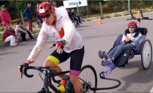 Óscar Caro hala la bicicleta de su hijo Luis David durante la edición 2018 de la triatlón de Paipa, Boyacá. Foto: Cortesía Team Caro Wagner